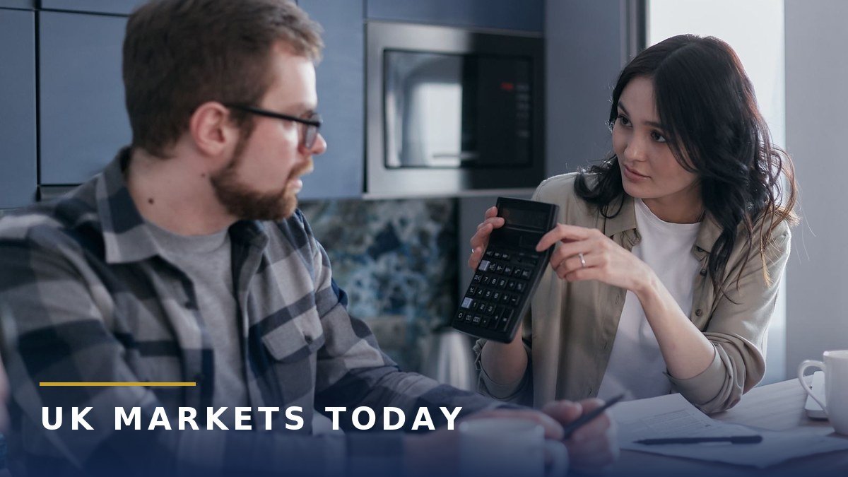 A couple at a kitchen table working out their joint savings together with a calculator and paperwork