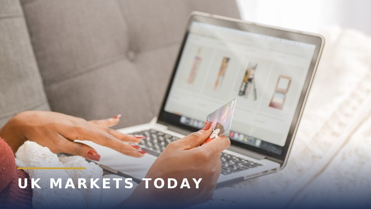 Woman shopping online on a laptop, holding a bank card. Photo by Kindel Media on Pexels.